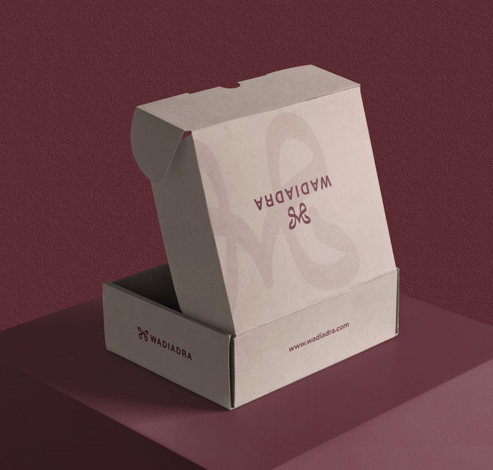 Wadi Adra packaging box opening on a maroon surface